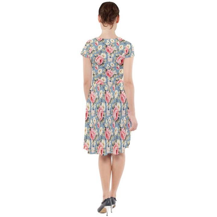 Back view of Vintage Rose Cap Sleeve Midi Dress showcasing floral pattern and pockets on a greyish-blue background.