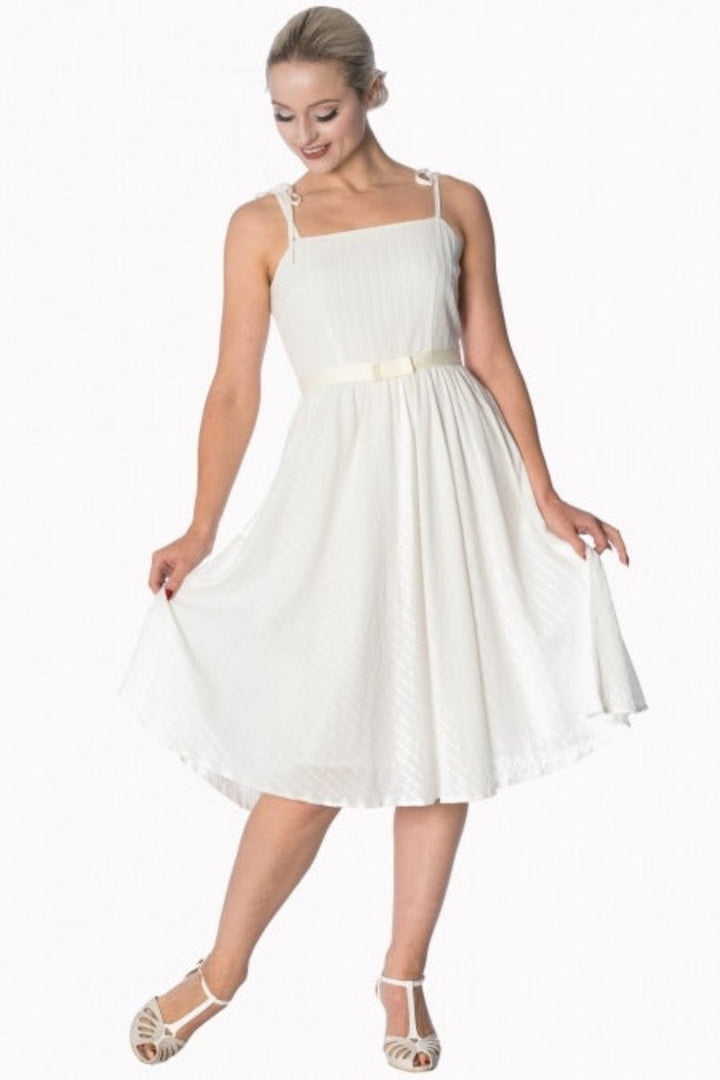 Woman in a white strappy sundress with bow tie, showcasing elegance and style for any occasion.