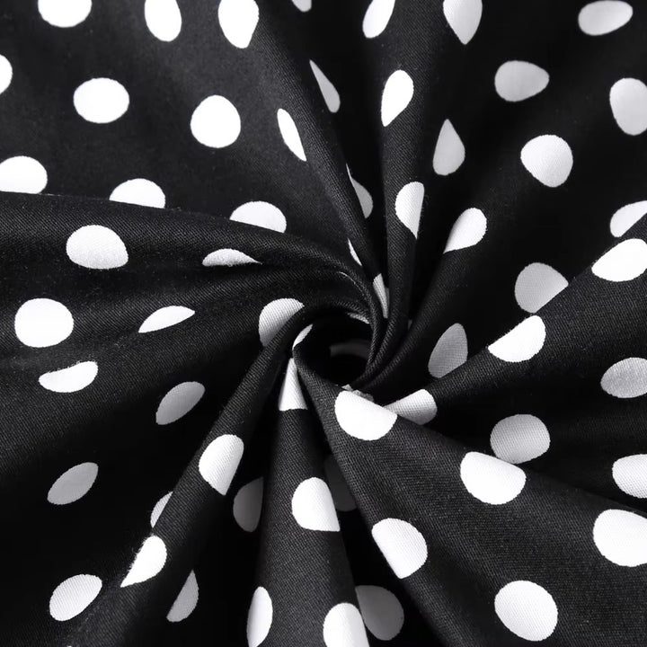 Close-up of black fabric with white polka dots, showcasing the playful pattern ideal for vintage fashion styles.