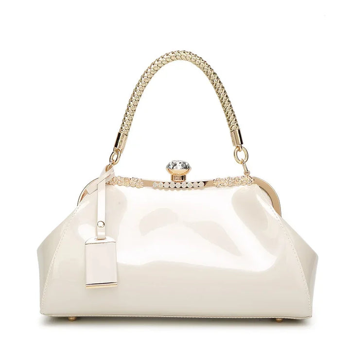 Elegant white patent handbag with a braided handle and rhinestone clip lock, perfect for sophisticated styling.