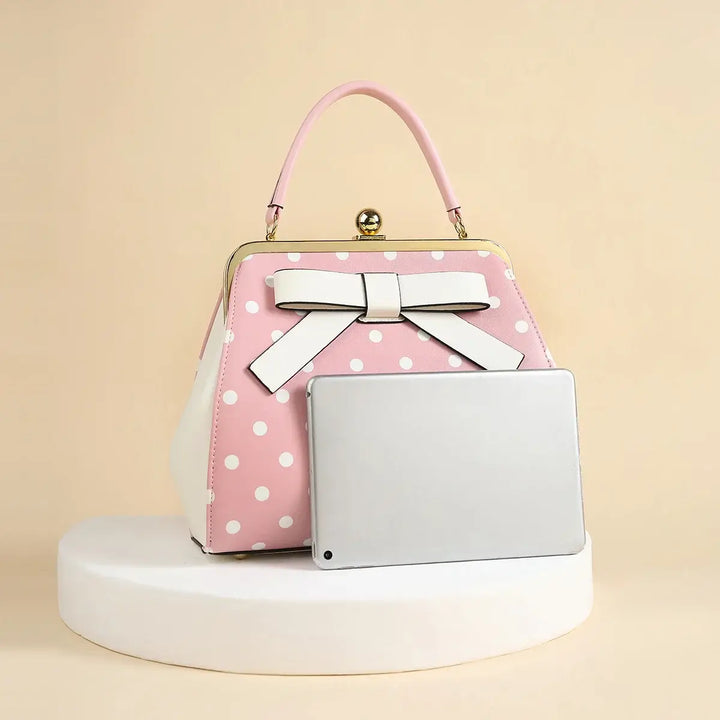 Pink polka dot rockabilly handbag with white bow, featuring a vintage kiss-lock closure.