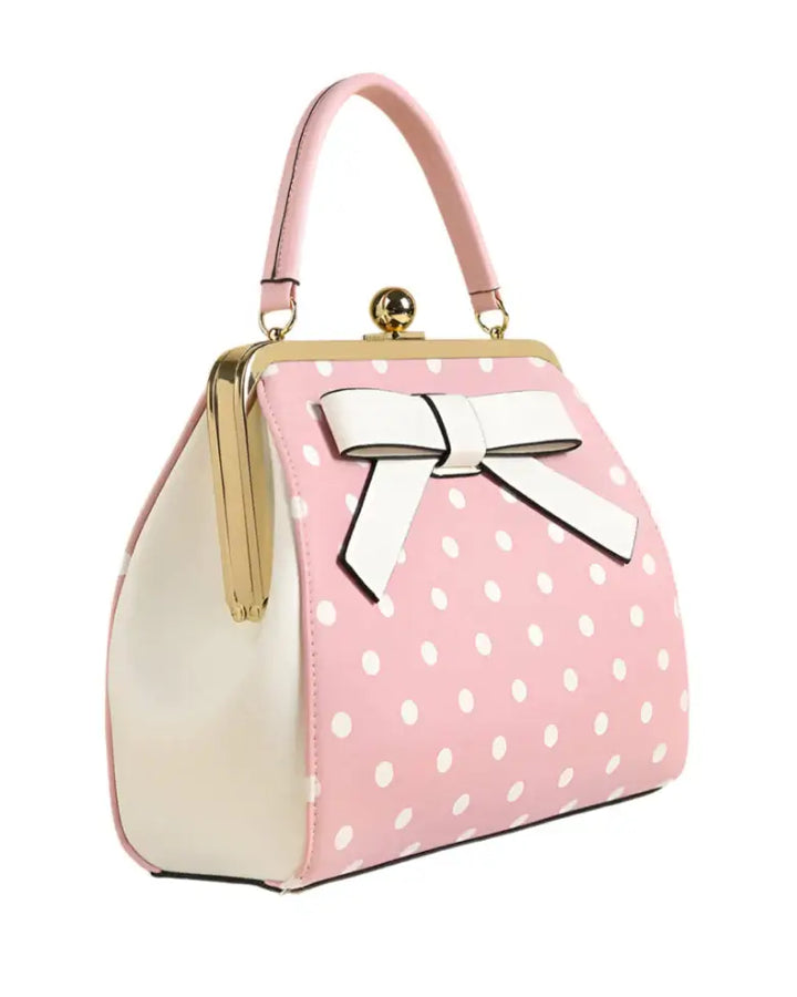 Pink polka dot rockabilly handbag with a vintage kiss-lock closure and white bow detail.