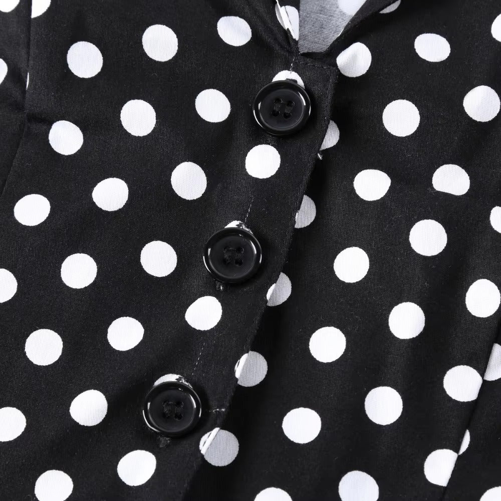 Close-up of black polka dot fabric with black buttons on a vintage swing dress, showcasing retro style and elegance.