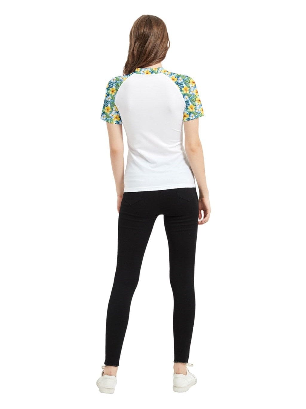 Back view of a woman wearing the Lets Luau short sleeve rashie with tropical floral sleeves and black leggings.